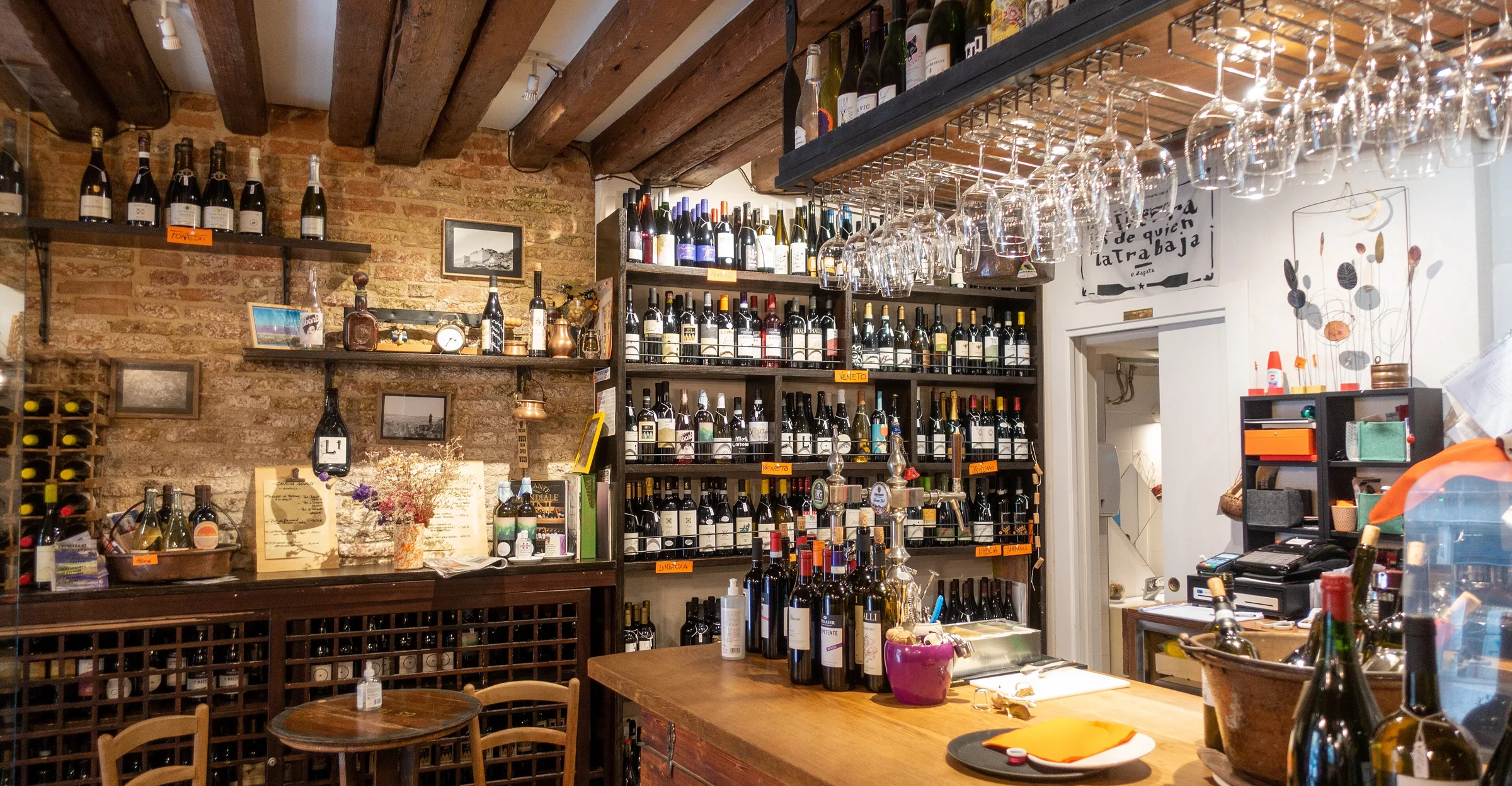 Il banco di un bacaro veneziano: bottiglie, legno, bicchieri appesi